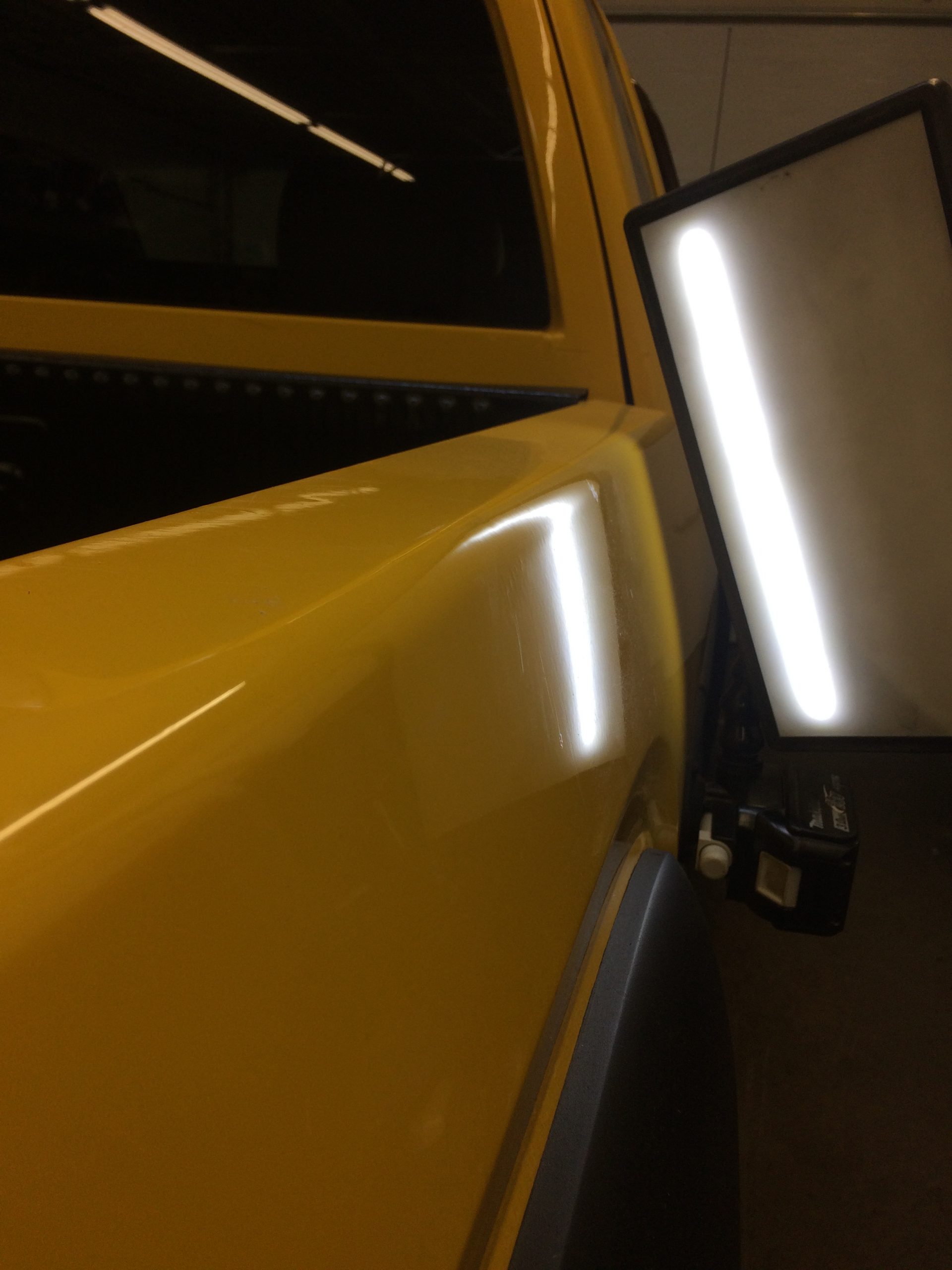 The same vehicle panel with a clean reflection after paintless dent repair