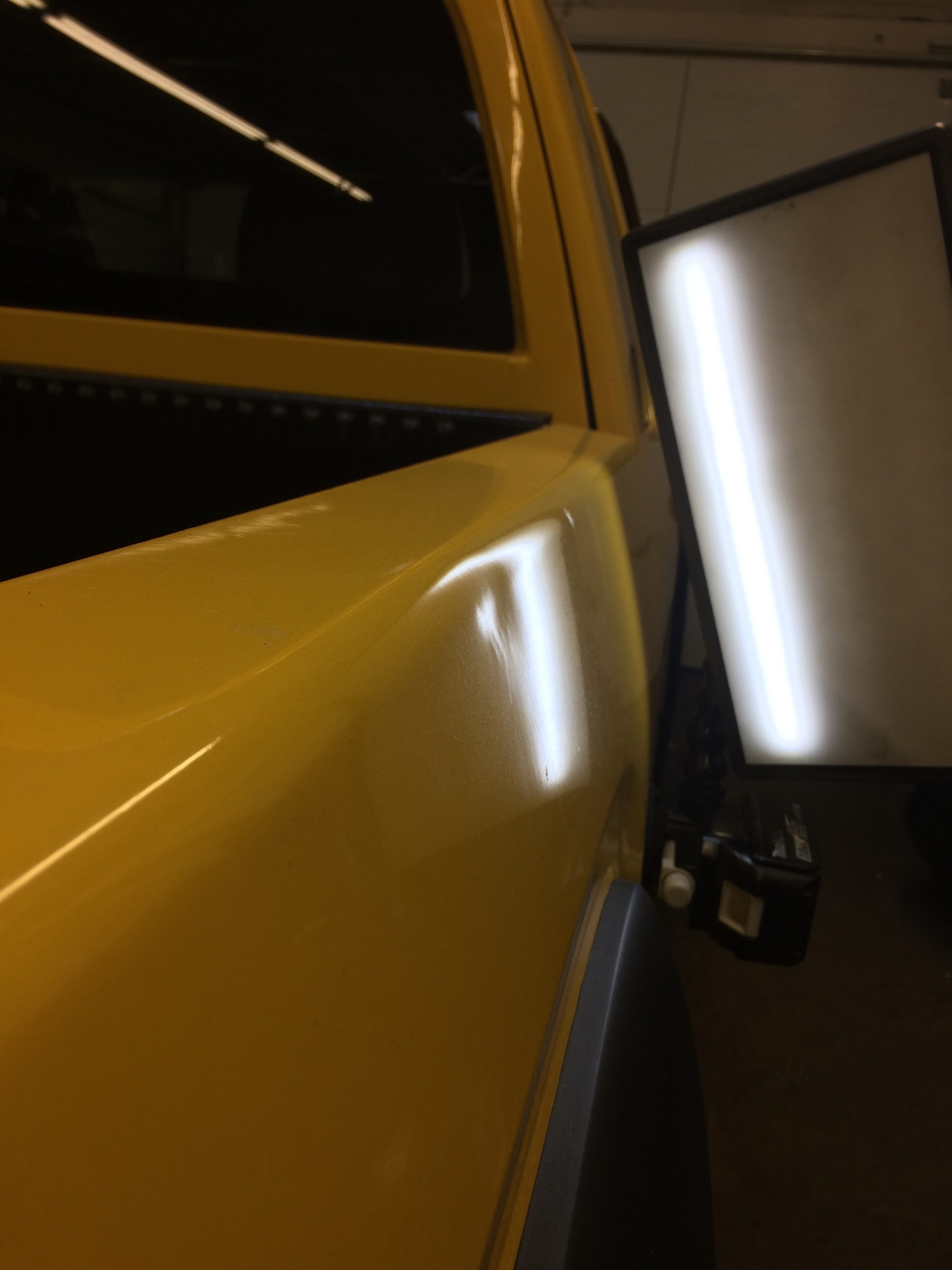 Vehicle panel with a visible dent before paintless dent repair